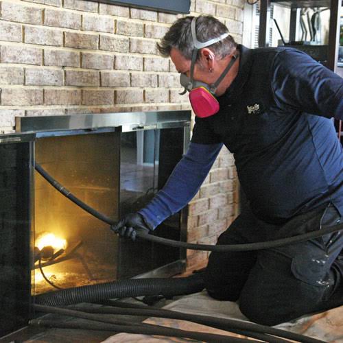 Technician cleaning a residential fireplace chimney